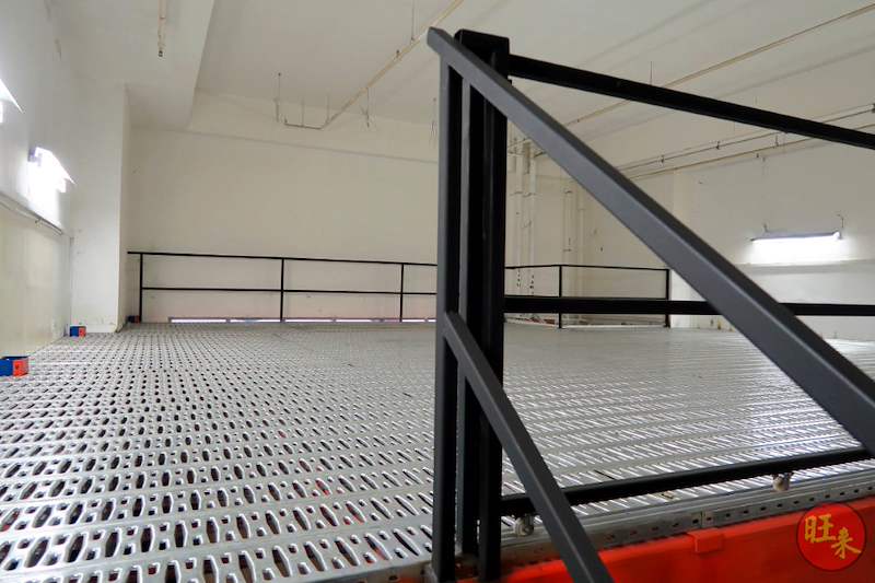 Mezzanine deck corner with black handrail posts and perforated steel decking, floor area empty - V6000 Racking - V6-7 | Wong Lye Racking, Singapore Racking Manufacturer