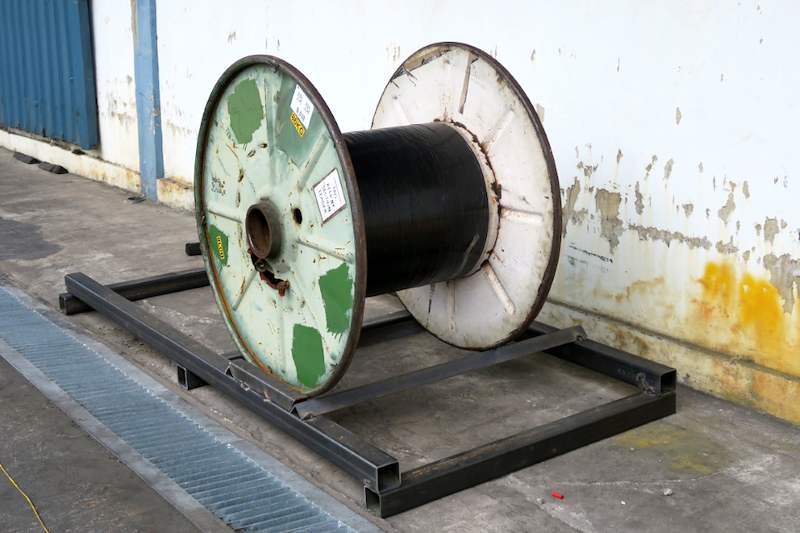 Cable drum resting on a steel base frame set over a floor drain grating beside the wall - V5000 Racking - V5-1 | Wong Lye Racking, Singapore Racking Manufacturer