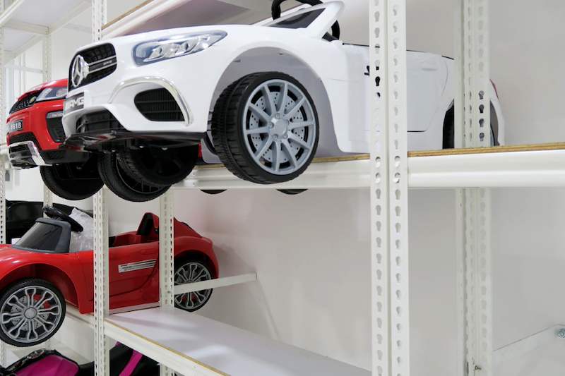 Close view of a white ride-on toy car on a boltless shelf, showing the slotted upright - Boltless Racking - B3 | Wong Lye Racking, Singapore Racking Manufacturer