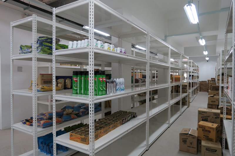 Long run of white boltless shelving along the wall with packaged food on the shelves, cartons on the floor - Boltless Racking - B6 | Wong Lye Racking, Singapore Racking Manufacturer