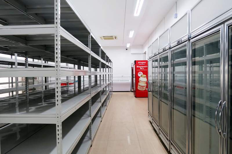Boltless shelving rows beside glass-door chillers and a drinks fridge - Boltless Racking - B5 | Wong Lye Racking, Singapore Racking Manufacturer