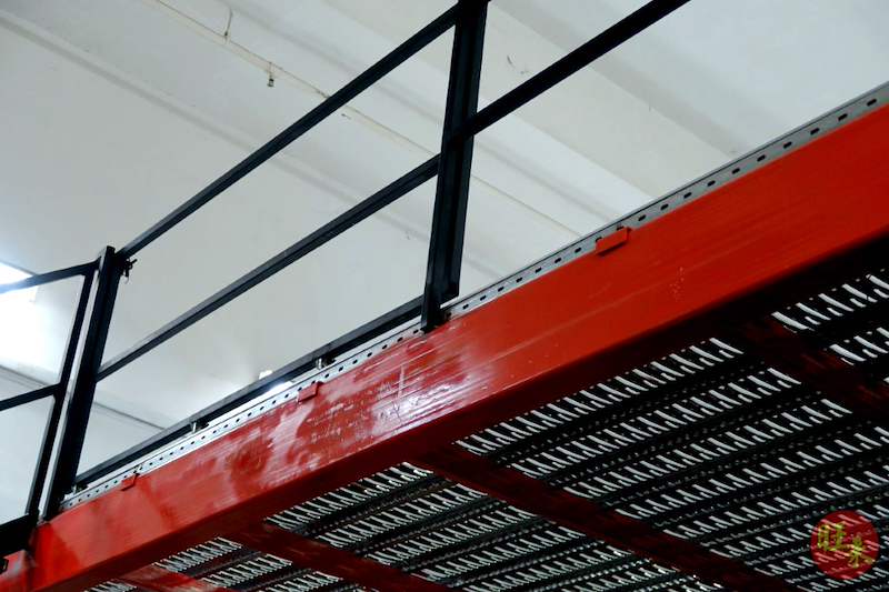 Mezzanine deck edge with red beam, perforated steel decking and black railing posts - V6000 Racking - V6-7 | Wong Lye Racking, Singapore Racking Manufacturer