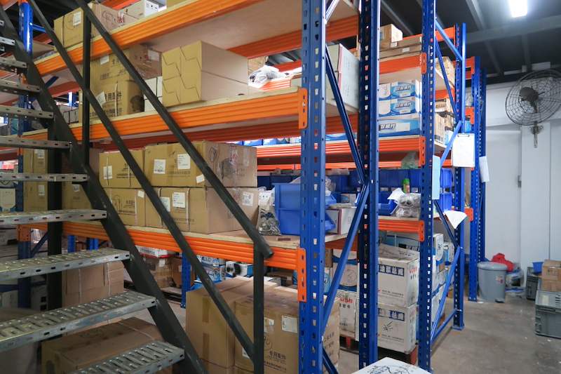 Staircase with perforated treads rising past racking bays full of cartons - V5000 Racking - V5-8 | Wong Lye Racking, Singapore Racking Manufacturer