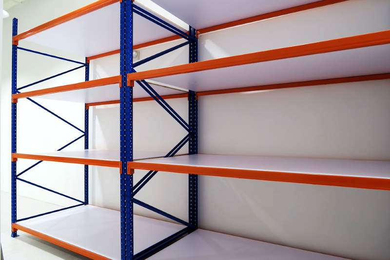 Long-span racking with orange beams and white decking boards on blue uprights, bays empty - Boltless Racking - B3 | Wong Lye Racking, Singapore Racking Manufacturer