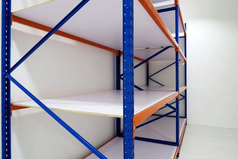 Blue-and-orange long-span racking bays with white decking boards, viewed from the side - Boltless Racking - B3 | Wong Lye Racking, Singapore Racking Manufacturer