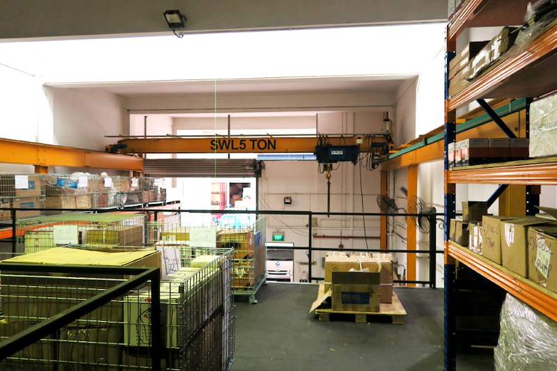 Mezzanine deck with black edge railing beside an overhead crane runway, wire cages and pallet racking on the deck - V5000 Racking - V5-8 | Wong Lye Racking, Singapore Racking Manufacturer