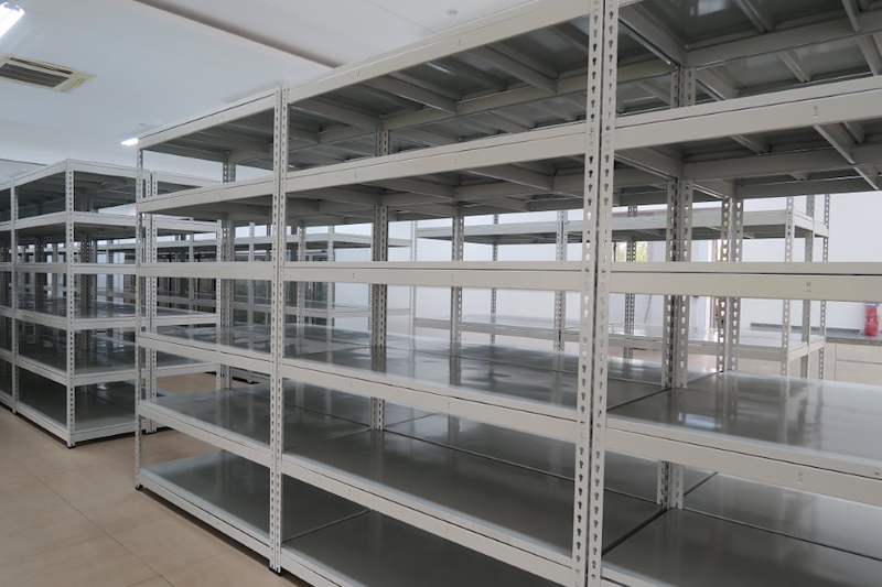 Grey boltless shelving bays with five shelf levels, fire extinguisher on the wall behind - Boltless Racking - B5 | Wong Lye Racking, Singapore Racking Manufacturer