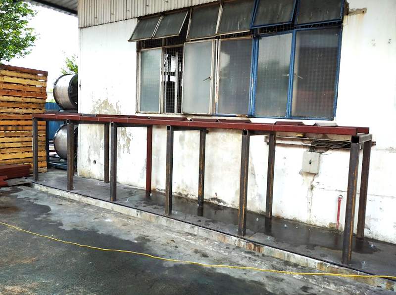 Empty steel rack frame in a yard beside a wall, base plates set on the raised kerb - V5000 Racking - V5-1 | Wong Lye Racking, Singapore Racking Manufacturer