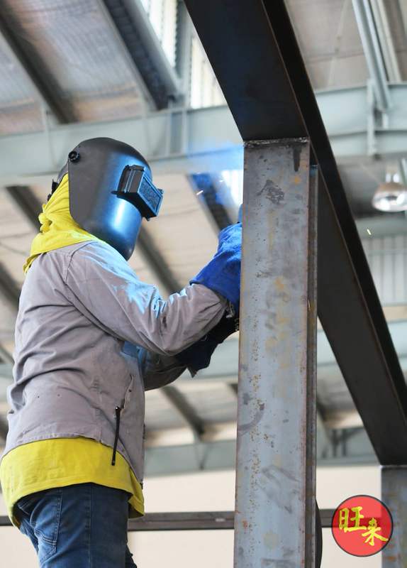 Welder in protective gear working on a steel column of the racking frame during fabrication - V10000 Racking - V10-1 | Wong Lye Racking, Singapore Racking Manufacturer