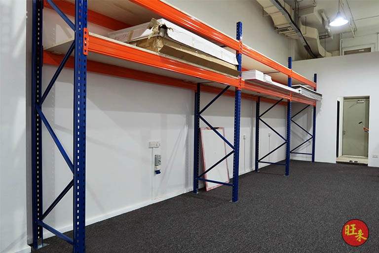 Two bays of blue-upright, orange-beam pallet racking with timber decking against the office wall, holding boards and a ladder - V5000 Racking - V5-13 | Wong Lye Racking, Singapore Racking Manufacturer