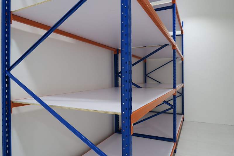 Long-span racking with blue uprights, orange beams and white board decking against the wall, close view - Boltless Racking - B3 | Wong Lye Racking, Singapore Racking Manufacturer