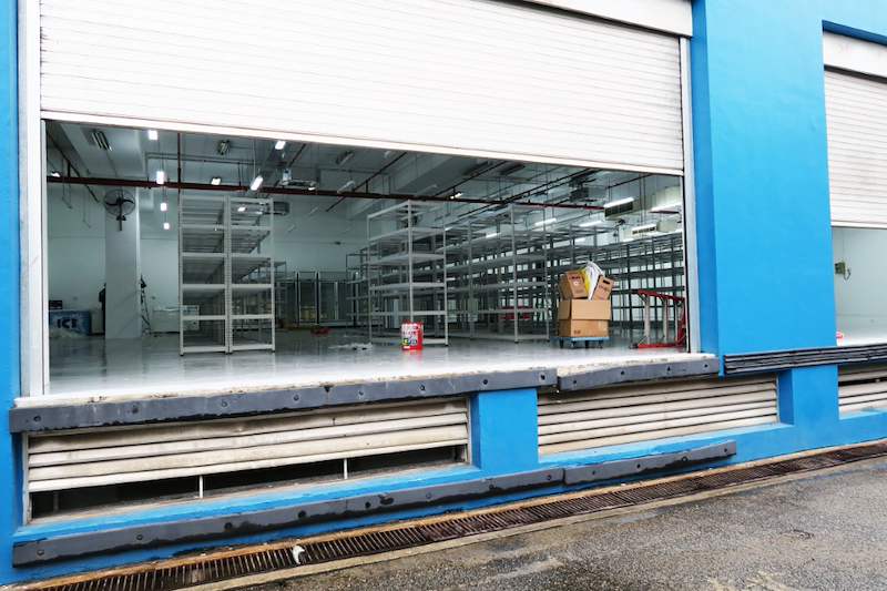 Rows of boltless shelving seen through the open roller shutter from the loading bay - Boltless Racking - B7 | Wong Lye Racking, Singapore Racking Manufacturer