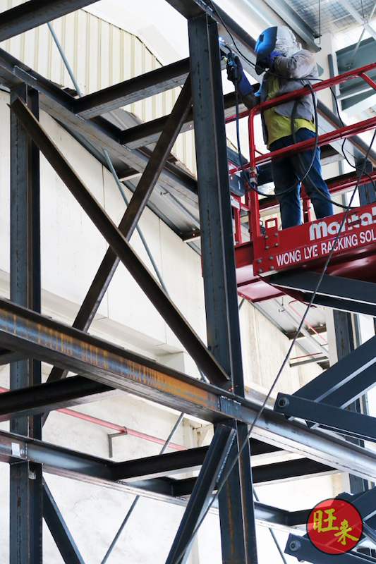 Installer on a boom lift bolting the bracing of the steel racking frame at height - V10000 Racking - V10-1 | Wong Lye Racking, Singapore Racking Manufacturer