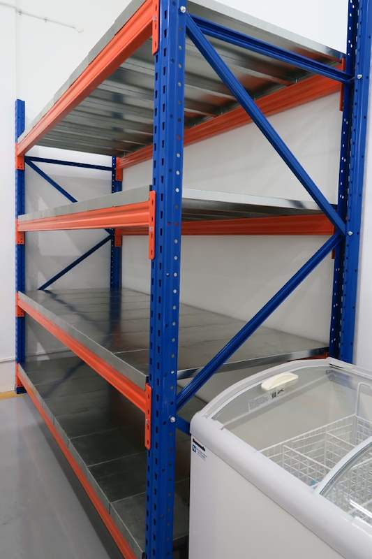 Blue-and-orange long-span racking bay with four steel-decked levels next to a chest freezer - Boltless Racking - B8 | Wong Lye Racking, Singapore Racking Manufacturer
