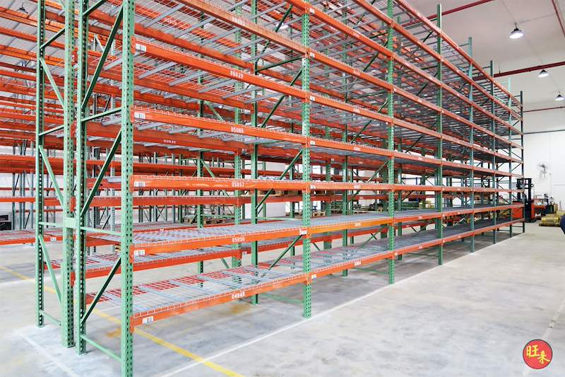 Long pallet racking run with orange beams and mesh decks, bays empty, forklift at the end - V3000 Racking - V3-3 | Wong Lye Racking, Singapore Racking Manufacturer