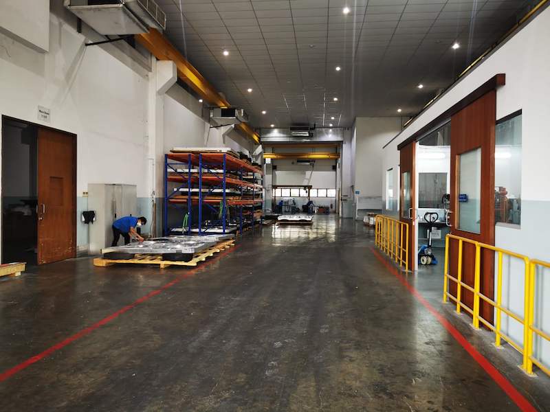Workshop aisle with the V3000 racking run in the distance and steel plates on pallets by the door - V3000 Racking - V3-1 | Wong Lye Racking, Singapore Racking Manufacturer