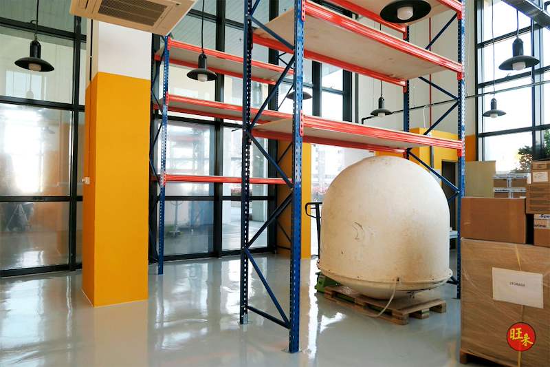 V3000 racking bay with orange beams and plywood decking beside an orange partition, cartons and a palletised item below - V3000 Racking - V3-4 | Wong Lye Racking, Singapore Racking Manufacturer