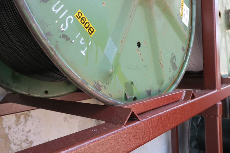 Cable drum flange resting in the V-shaped steel cradle beam of the red-oxide rack - V5000 Racking - V5-1 | Wong Lye Racking, Singapore Racking Manufacturer