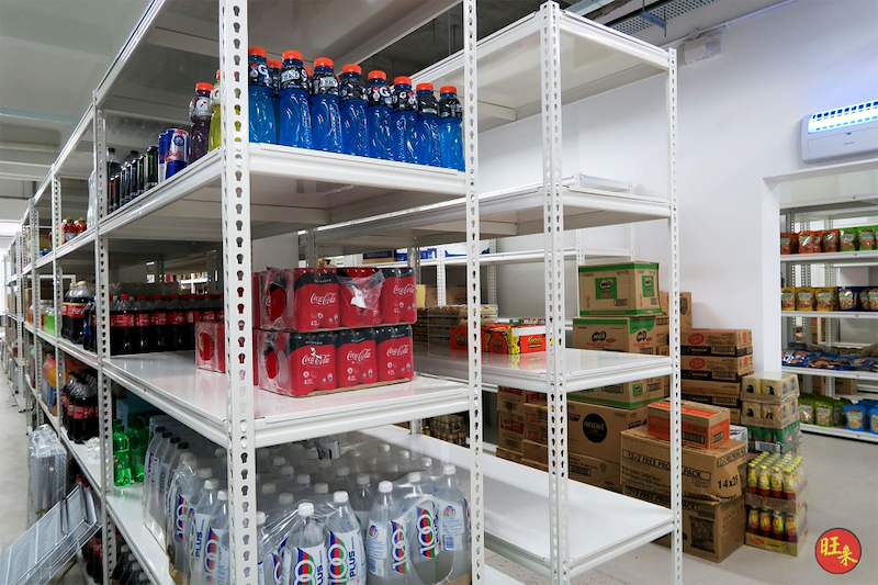 Cases of bottled drinks on white boltless shelving with cartons stacked on the floor - Boltless Racking - B6 | Wong Lye Racking, Singapore Racking Manufacturer