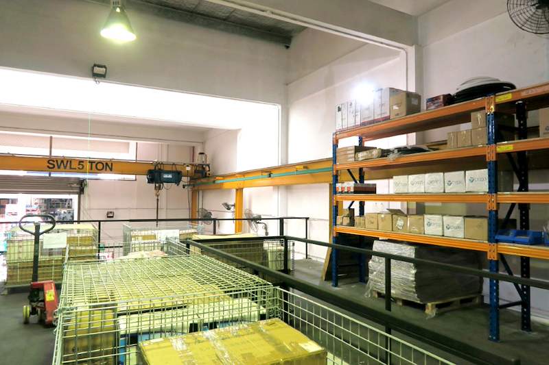 Mezzanine deck with black edge railing, wire cages and racking bays of cartons, overhead crane beyond - V5000 Racking - V5-8 | Wong Lye Racking, Singapore Racking Manufacturer