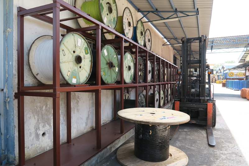 Two-tier steel cable-drum rack with a forklift and an empty drum in the yard in front - V5000 Racking - V5-1 | Wong Lye Racking, Singapore Racking Manufacturer