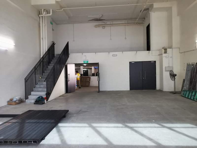Staircase with black balustrade rising to the mezzanine, deck panels on the floor in front - V5000 Racking - V5-9 | Wong Lye Racking, Singapore Racking Manufacturer