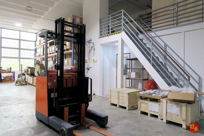 Reach truck below the mezzanine staircase with timber crates and cartons on the warehouse floor - V5000 Racking - V5-19 | Wong Lye Racking, Singapore Racking Manufacturer