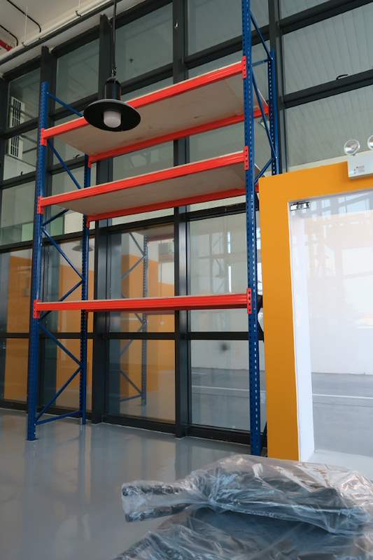 V3000 racking bay with plywood decking next to the glass-walled room, packaging on the floor - V3000 Racking - V3-4 | Wong Lye Racking, Singapore Racking Manufacturer