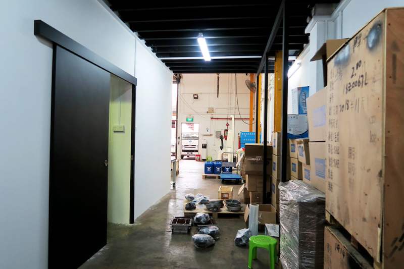 Sliding door and passage under the mezzanine with cartons and timber crates stacked alongside - V5000 Racking - V5-8 | Wong Lye Racking, Singapore Racking Manufacturer