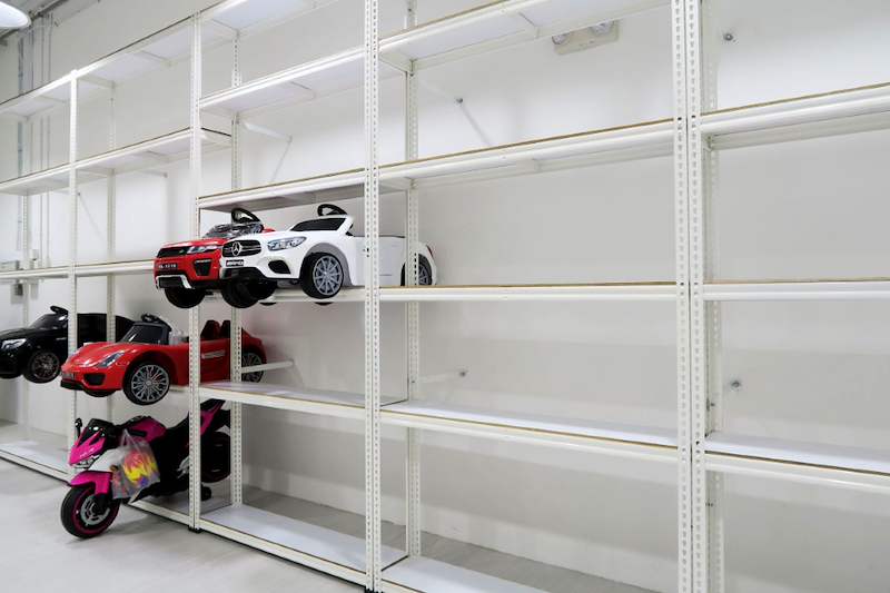 Long run of white boltless shelving with five levels, ride-on toy cars displayed on the lower shelves - Boltless Racking - B3 | Wong Lye Racking, Singapore Racking Manufacturer