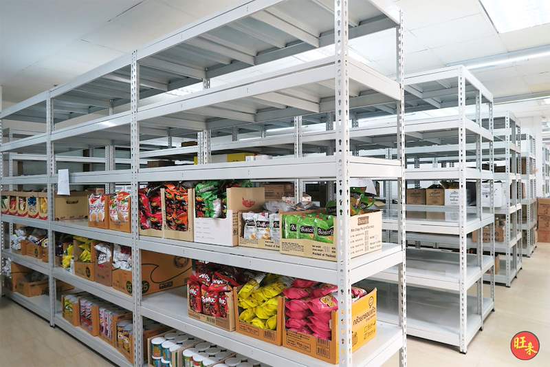 Grey boltless shelving bays stocked with bagged snacks and canned goods, more rows behind - Boltless Racking - B2 | Wong Lye Racking, Singapore Racking Manufacturer