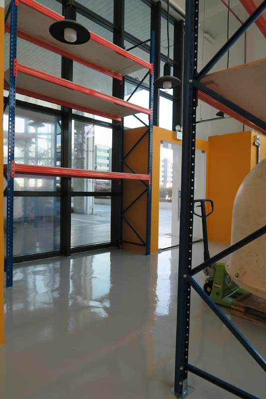 Blue upright with diagonal bracing and orange beams of the V3000 racking beside a glass wall - V3000 Racking - V3-4 | Wong Lye Racking, Singapore Racking Manufacturer