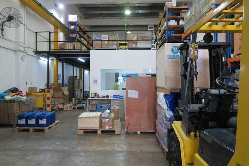 Ground floor under the mezzanine with a forklift, drums on pallets and timber crates, racking on the deck above - V5000 Racking - V5-8 | Wong Lye Racking, Singapore Racking Manufacturer