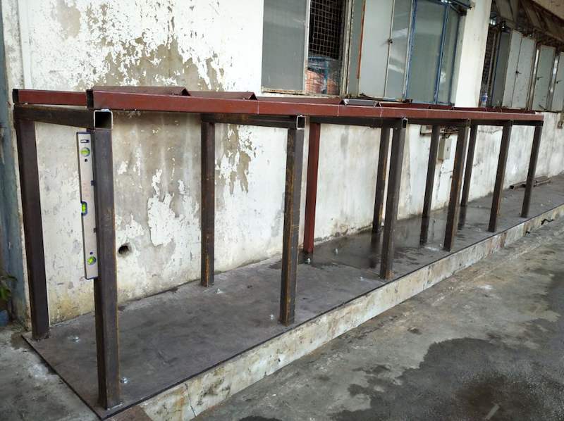 Steel uprights and top beams on a base plate, with a spirit level checking an upright - V5000 Racking - V5-1 | Wong Lye Racking, Singapore Racking Manufacturer