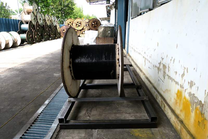 Cable drum seated on a steel base frame in the yard, with more drums stored beyond - V5000 Racking - V5-1 | Wong Lye Racking, Singapore Racking Manufacturer