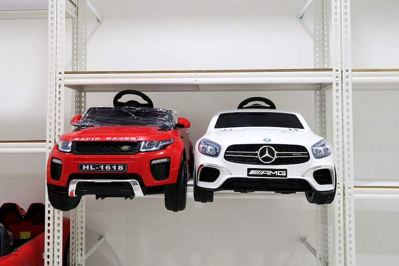 Red and white ride-on toy cars side by side on a white boltless shelf - Boltless Racking - B3 | Wong Lye Racking, Singapore Racking Manufacturer