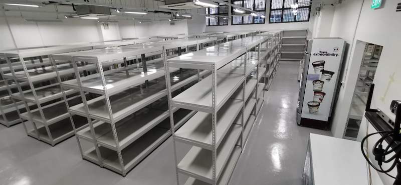 Rows of boltless shelving with steel shelves beside a glass-door drinks chiller - Boltless Racking - B1 | Wong Lye Racking, Singapore Racking Manufacturer