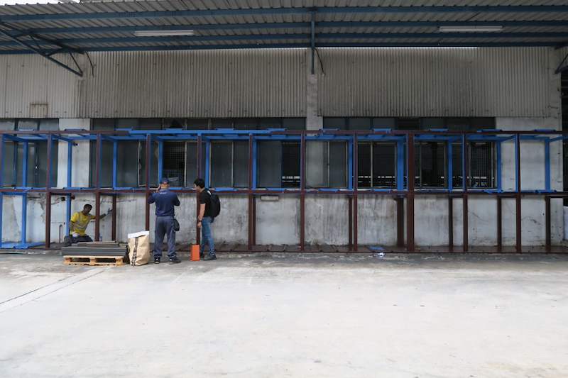 Installers assembling the two-tier steel rack frame along the wall, with a pallet of parts on the ground - V5000 Racking - V5-1 | Wong Lye Racking, Singapore Racking Manufacturer