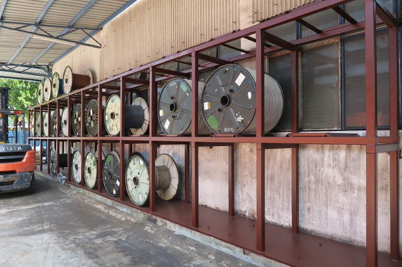 Cable drums stored two tiers high in a welded steel rack along an outdoor wall - V5000 Racking - V5-1 | Wong Lye Racking, Singapore Racking Manufacturer