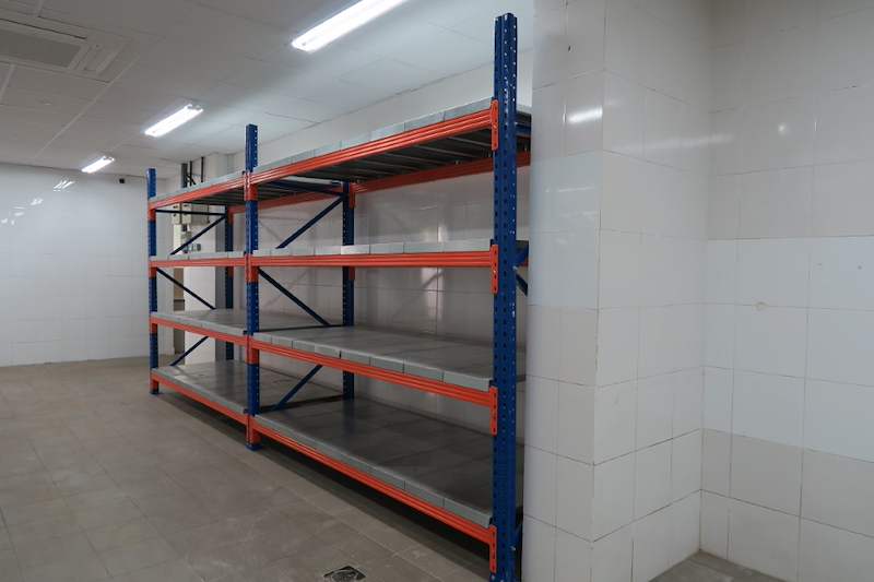 Long-span racking run with blue uprights and orange beams along the wall, viewed from the end - Boltless Racking - B5 | Wong Lye Racking, Singapore Racking Manufacturer