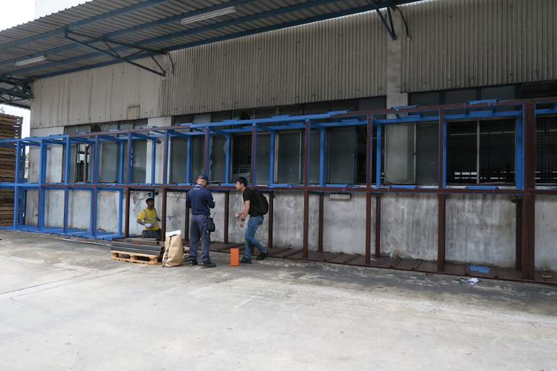 Two-tier steel rack frame being assembled along the wall, installers at work in the yard - V5000 Racking - V5-1 | Wong Lye Racking, Singapore Racking Manufacturer