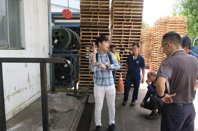 Installer and visitors on site beside the first upright frame of the drum rack, pallets stacked in the yard - V5000 Racking - V5-1 | Wong Lye Racking, Singapore Racking Manufacturer