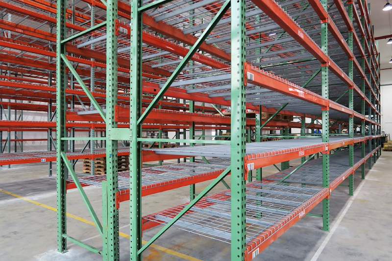 Mesh-decked pallet racking levels on green uprights and orange beams along the aisle - V3000 Racking - V3-3 | Wong Lye Racking, Singapore Racking Manufacturer