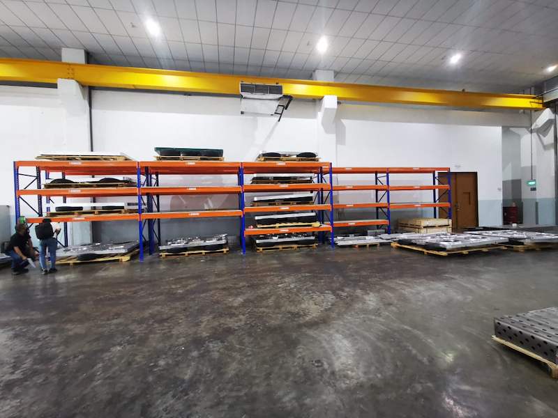 Long run of V3000 racking bays along the workshop wall with steel parts on the levels, overhead crane above - V3000 Racking - V3-1 | Wong Lye Racking, Singapore Racking Manufacturer