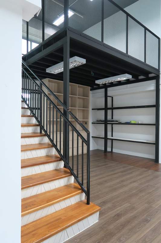 Black steel mezzanine loft with timber staircase and open shelving underneath, viewed from the doorway - V5000 Racking - V5-16 | Wong Lye Racking, Singapore Racking Manufacturer