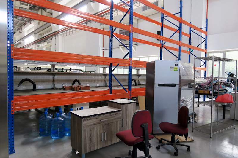 V3000 racking run above a workbench and office chairs, wire shelving beside - V3000 Racking - V3-5 | Wong Lye Racking, Singapore Racking Manufacturer