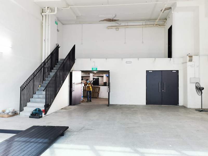 Staircase with black balustrade to the mezzanine, deck panels staged on the floor below - V5000 Racking - V5-9 | Wong Lye Racking, Singapore Racking Manufacturer