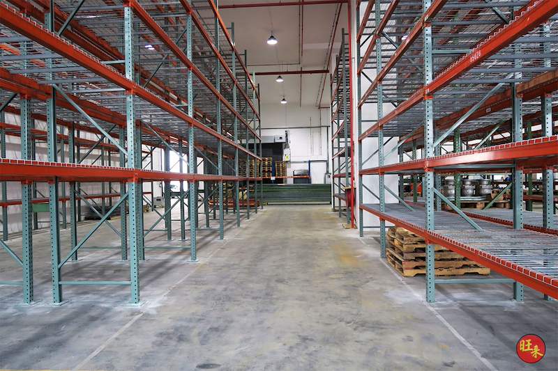 Main aisle between tall pallet racking runs with wire mesh decks, pallets stored at the far end - V3000 Racking - V3-3 | Wong Lye Racking, Singapore Racking Manufacturer