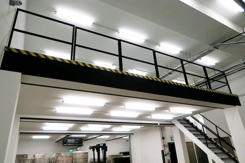 Looking up at the mezzanine deck edge with black railing, hazard striping and the staircase beside it - V8000 Racking - V8-6 | Wong Lye Racking, Singapore Racking Manufacturer