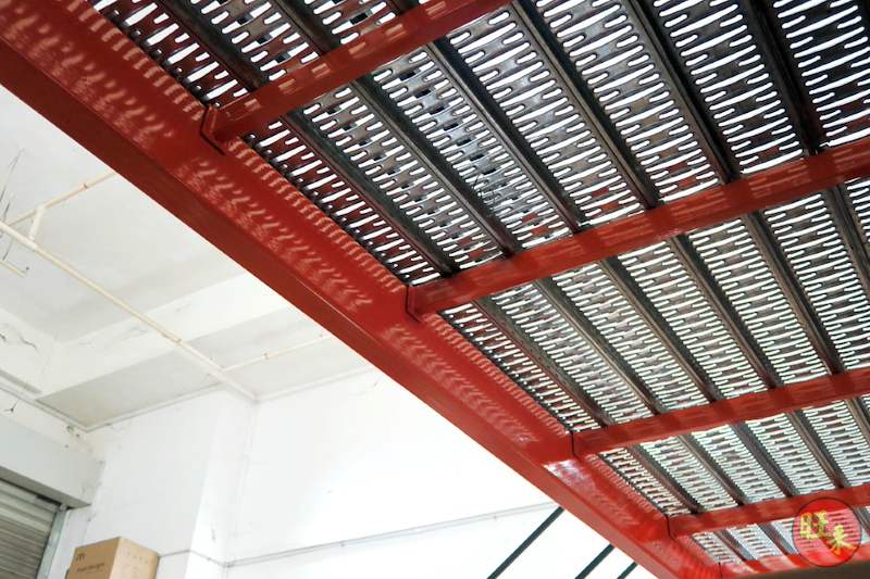 Red mezzanine beams carrying perforated steel deck panels, viewed from below - V6000 Racking - V6-7 | Wong Lye Racking, Singapore Racking Manufacturer